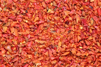 Photo of Aromatic spice. Red chili pepper flakes as background, top view