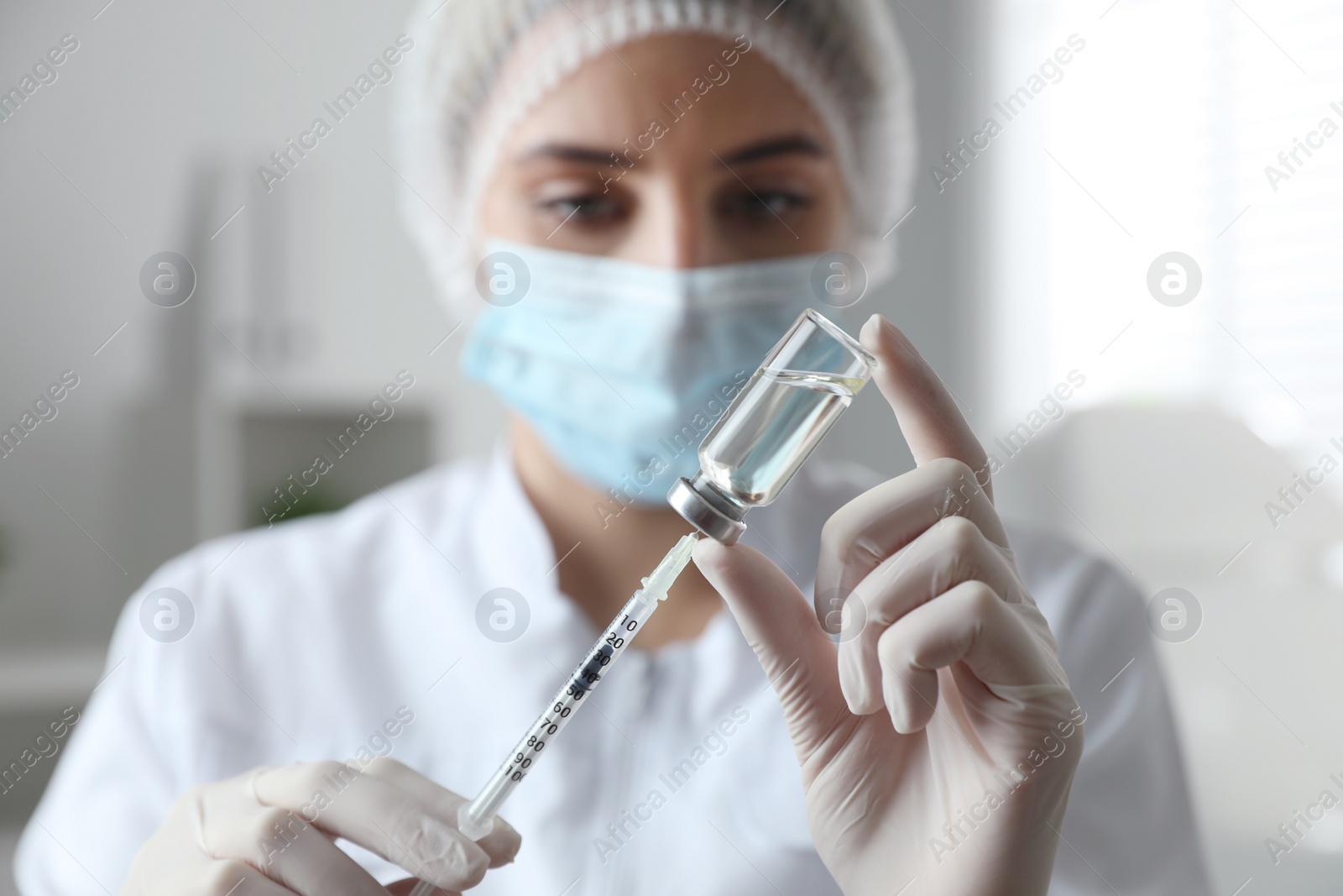 Photo of Doctor filling syringe with medication in clinic, focus on hands. Vaccination and immunization