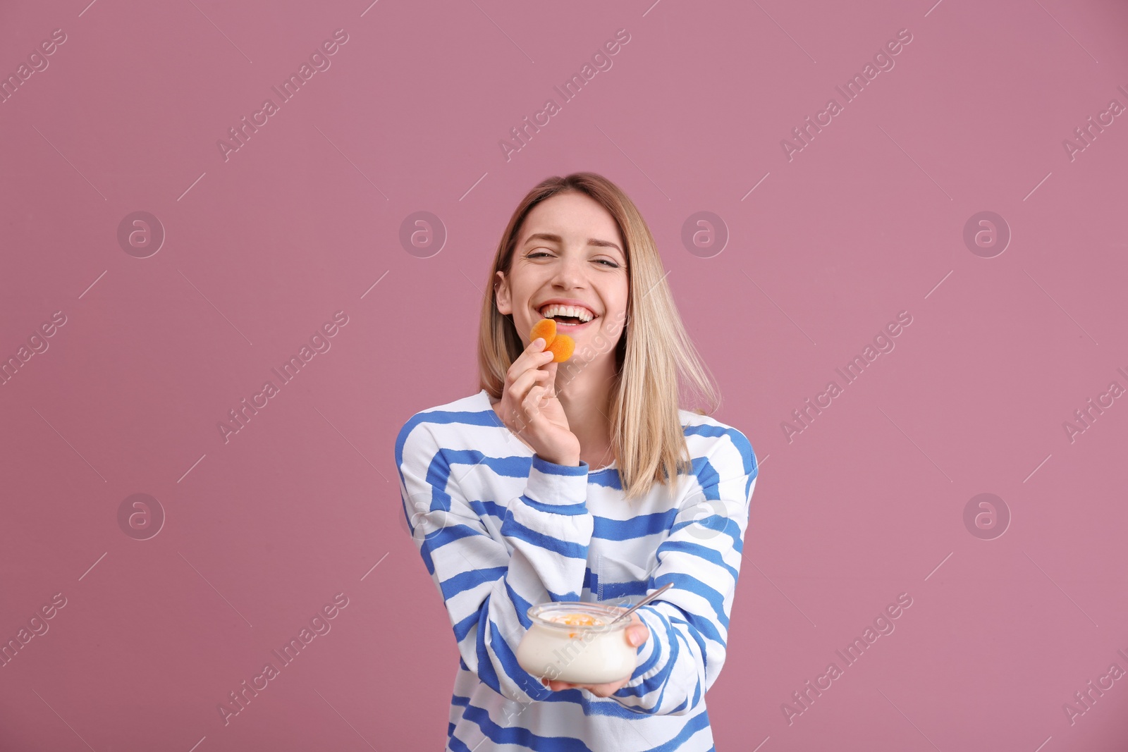 Photo of Young attractive woman eating tasty yogurt on color background