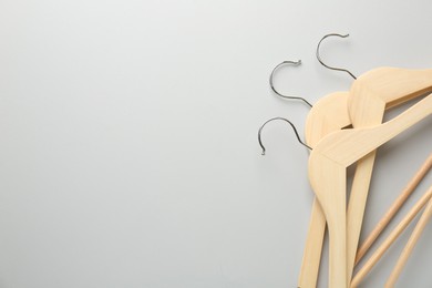 Wooden hangers on light gray background, top view. Space for text