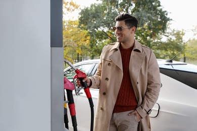 Photo of Man taking fuel pump nozzle at self service gas station