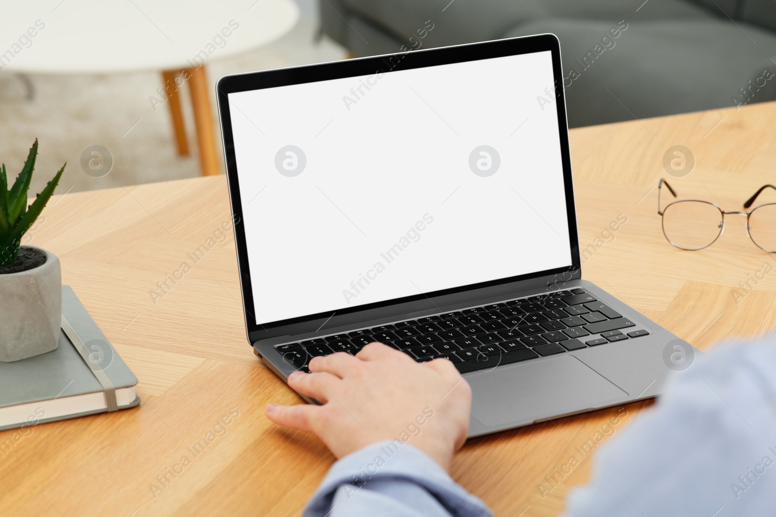 Photo of Man working with laptop at wooden table indoors, closeup