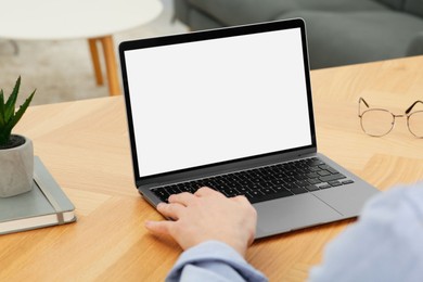 Photo of Man working with laptop at wooden table indoors, closeup