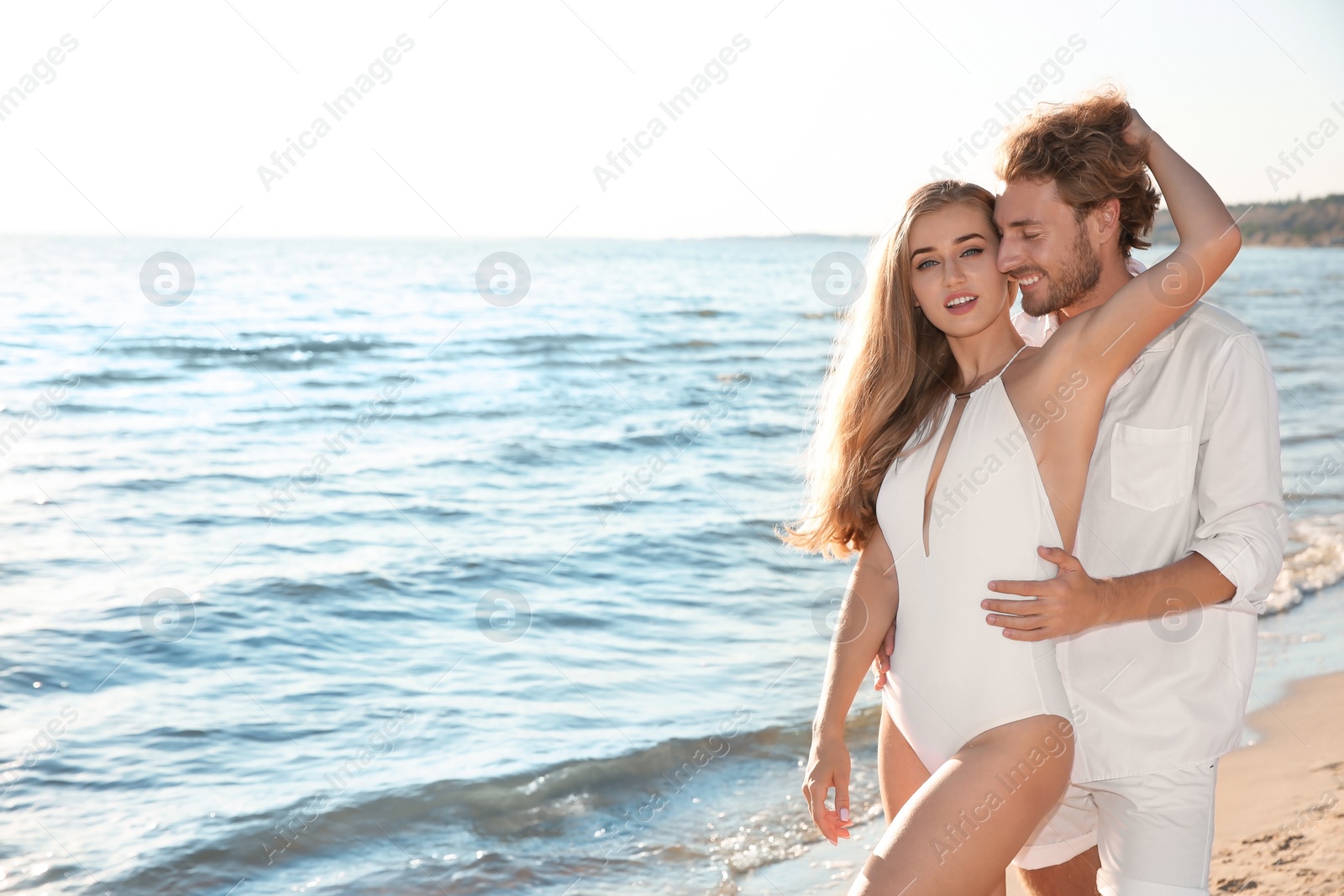Photo of Romantic young couple spending time together on beach. Space for text