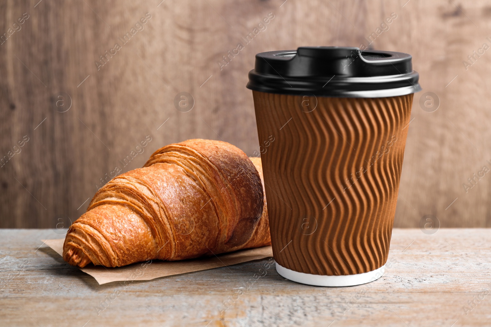 Photo of Tasty fresh croissant and drink on wooden table