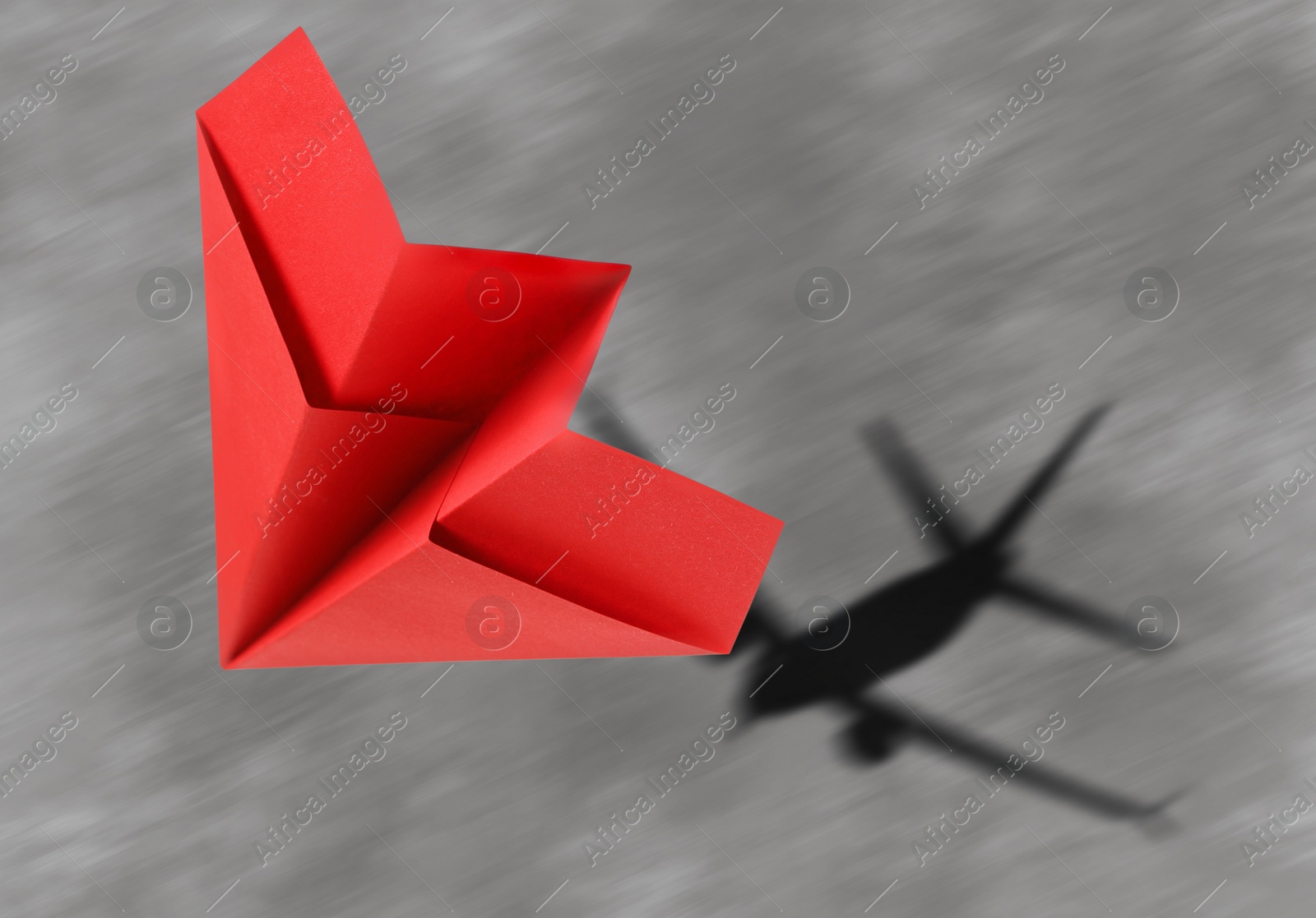 Image of Flying paper plane and shadow of a real airplane on asphalt