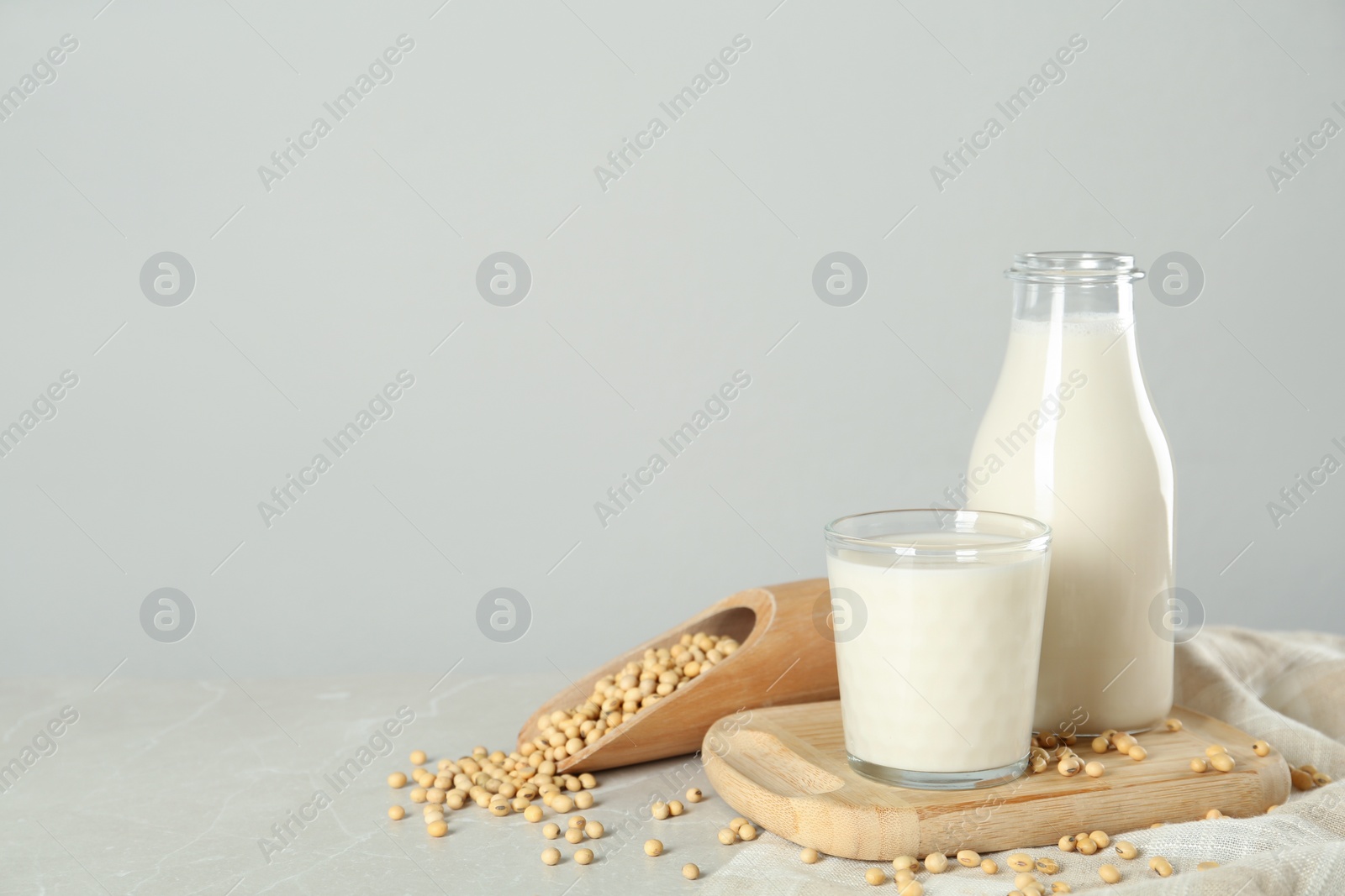 Photo of Fresh soy milk and beans on light grey table, space for text