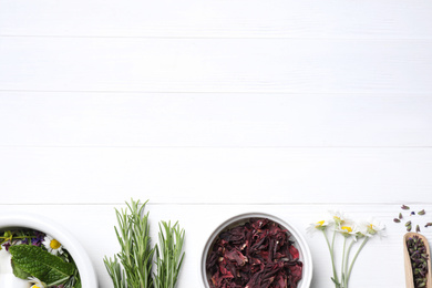 Flat lay composition with healing herbs on white wooden table. Space for text