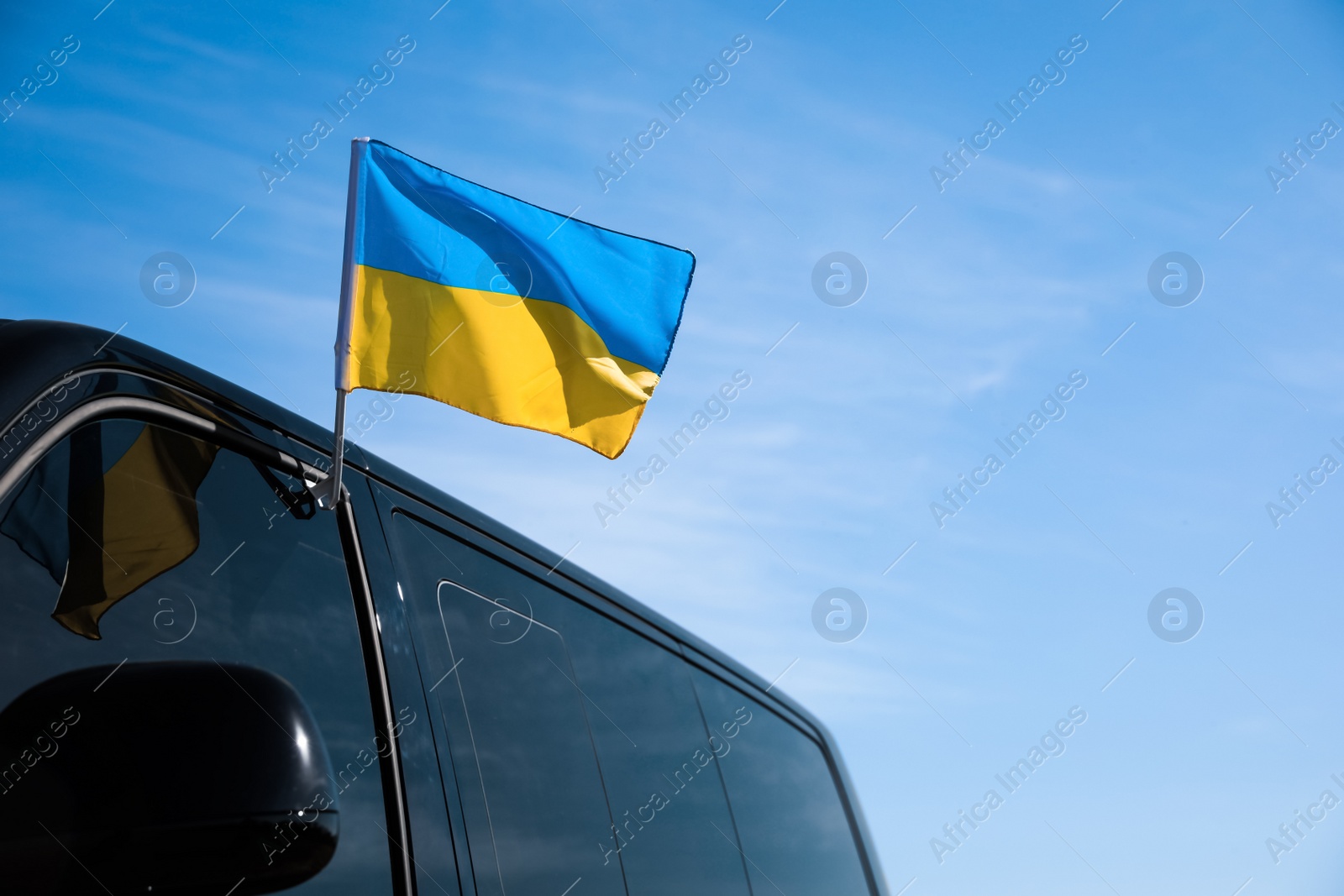 Photo of National flag of Ukraine on car window outdoors. Space for text