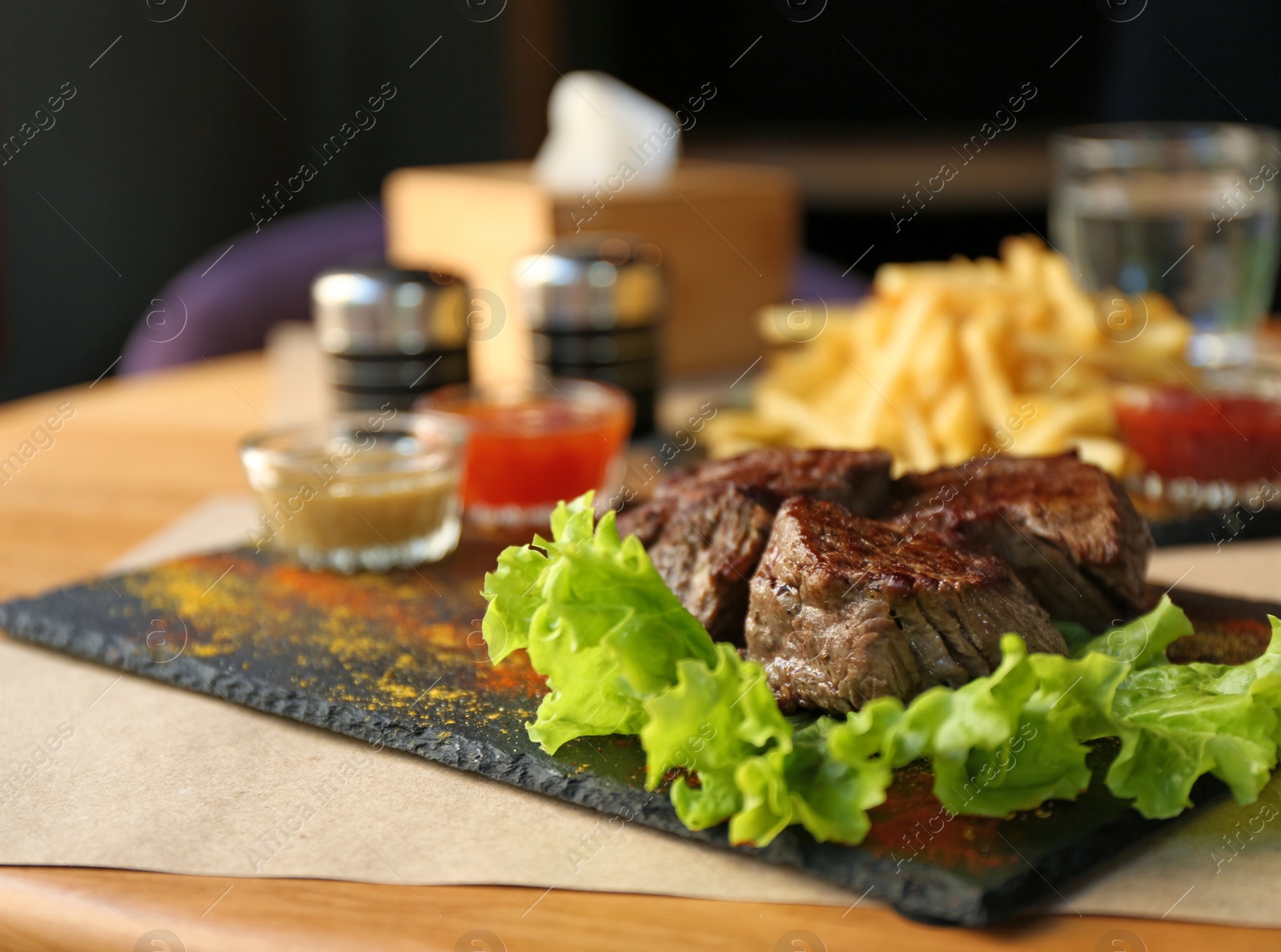 Photo of Tasty pieces of shish kebab served on slate plate in cafe