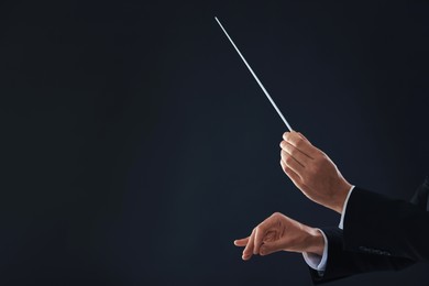 Photo of Professional conductor with baton on black background, closeup. Space for text