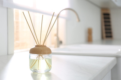 Photo of Aromatic reed air freshener on white table indoors. Space for text