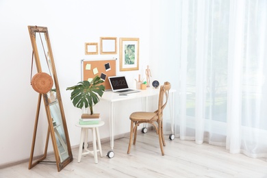 Stylish workplace with laptop on table in room