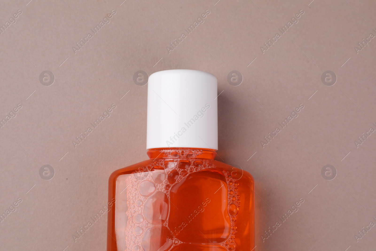 Photo of Fresh mouthwash in bottle on beige background, top view