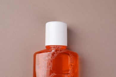 Fresh mouthwash in bottle on beige background, top view