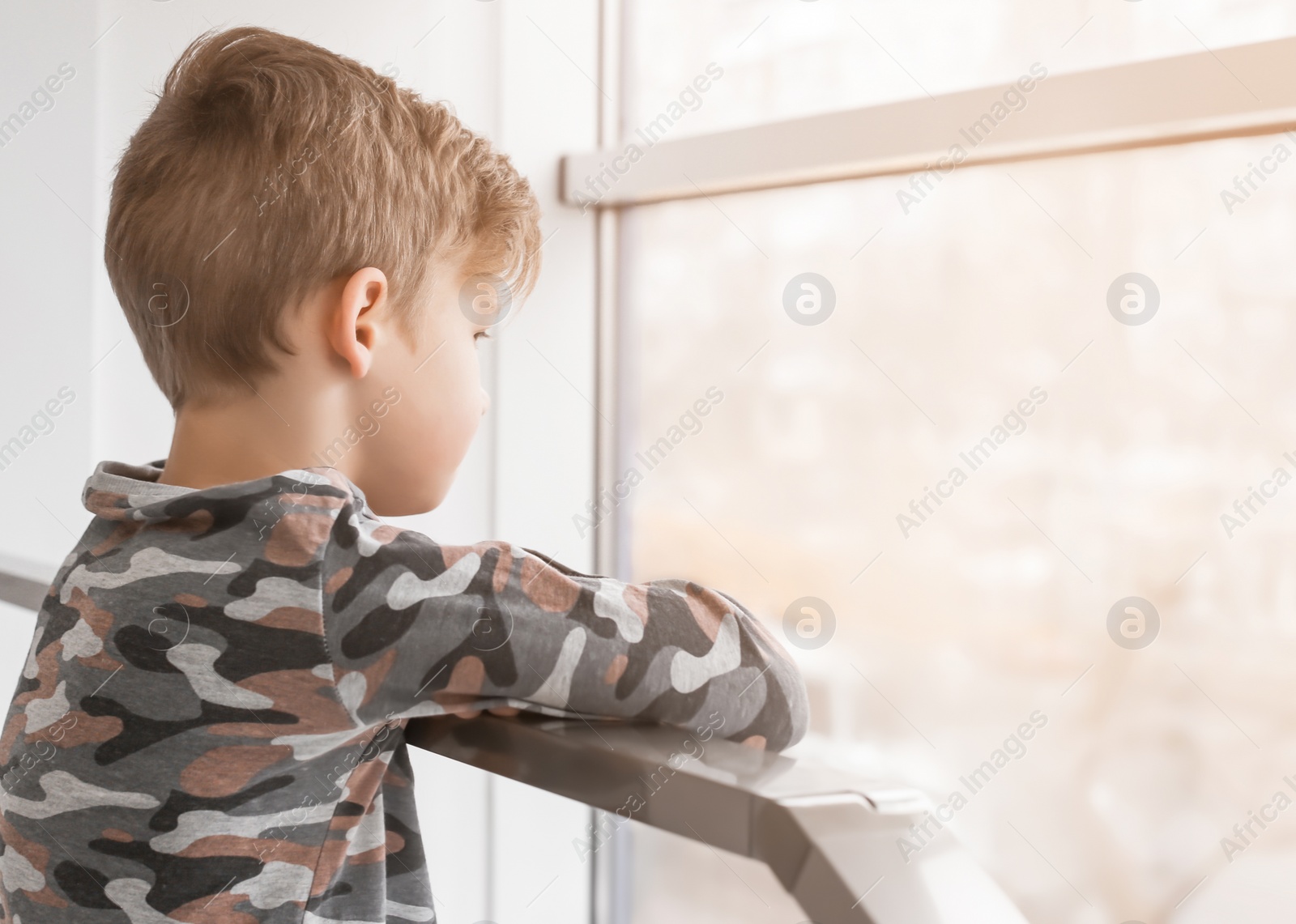 Photo of Lonely little boy near window indoors. Child autism