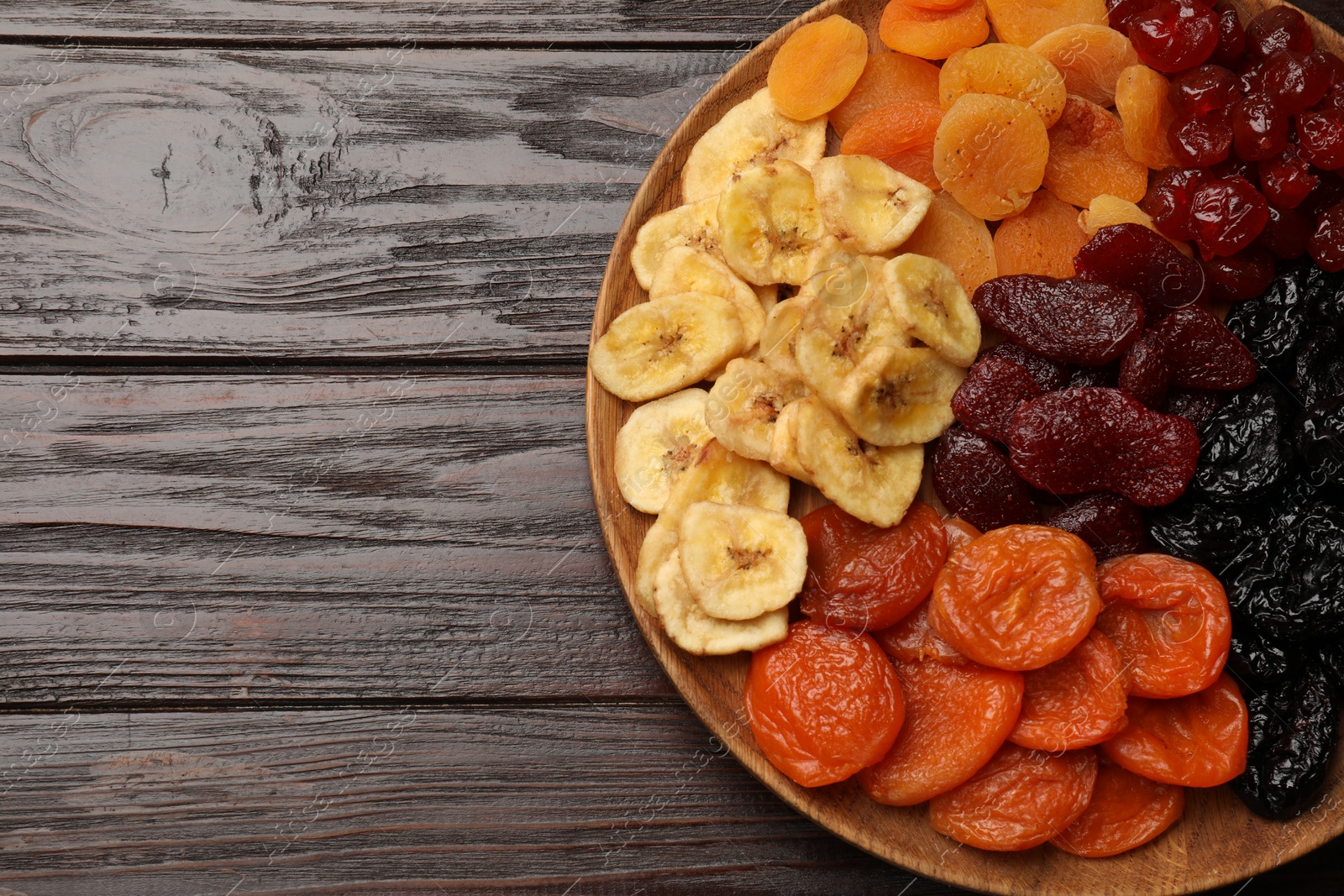 Photo of Delicious dried fruits on wooden table, top view. Space for text