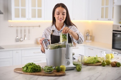 Photo of Young woman making tasty fresh juice at table in kitchen