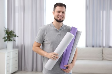 Man with stylish wallpaper rolls in room