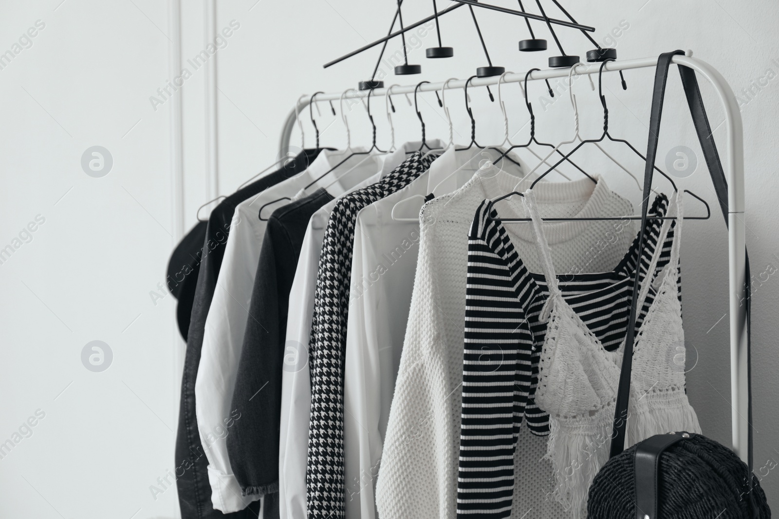 Photo of Rack with stylish clothes near white wall, closeup