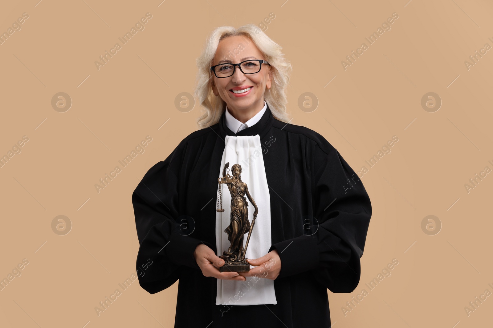 Photo of Smiling senior judge with figure of Lady Justice on light brown background