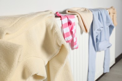Photo of Clean clothes on white heating radiator indoors, closeup