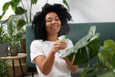 Photo of Houseplant care. Woman spraying beautiful monstera with water indoors. Houseplant care