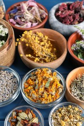 Many different herbs in bowls on blue wooden table