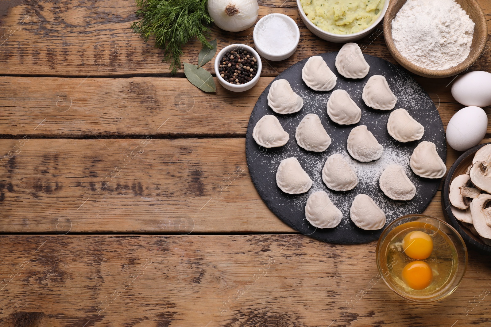 Photo of Raw dumplings (varenyky) and ingredients on wooden table, flat lay. Space for text