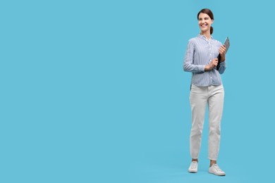 Photo of Happy secretary with clipboard on light blue background, space for text
