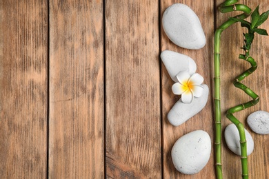 Photo of Flat lay composition with spa stones and space for text on wooden background