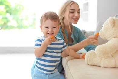 Photo of Woman playing with child while feeding him at home. Healthy baby food