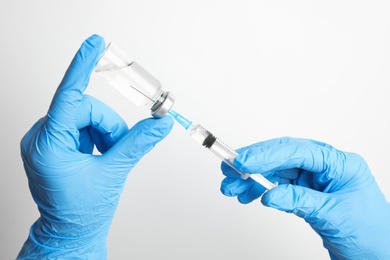 Photo of Doctor filling syringe with medication on white background, closeup. Vaccination and immunization