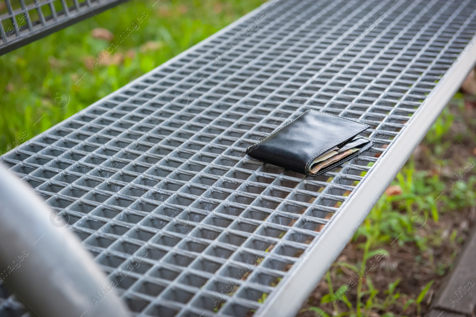 Photo of Black wallet on metal bench outdoors, space for text. Lost and found