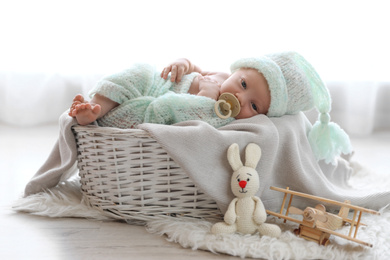 Photo of Cute newborn baby lying on plaid in basket at home