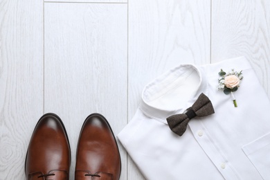 Photo of Wedding shoes and shirt on white wooden floor, flat lay. Space for text