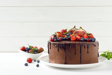 Fresh delicious homemade chocolate cake with berries on table against wooden background