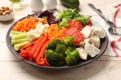 Balanced diet and healthy foods. Plate with different delicious products on light wooden table, closeup