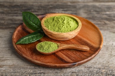Photo of Spoon and bowl with green matcha powder on wooden table, closeup