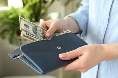 Money exchange. Woman putting dollar banknotes into wallet on blurred background, closeup