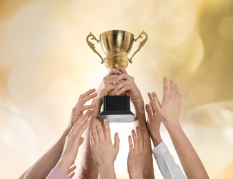 Image of People with gold trophy cup on color background, closeup