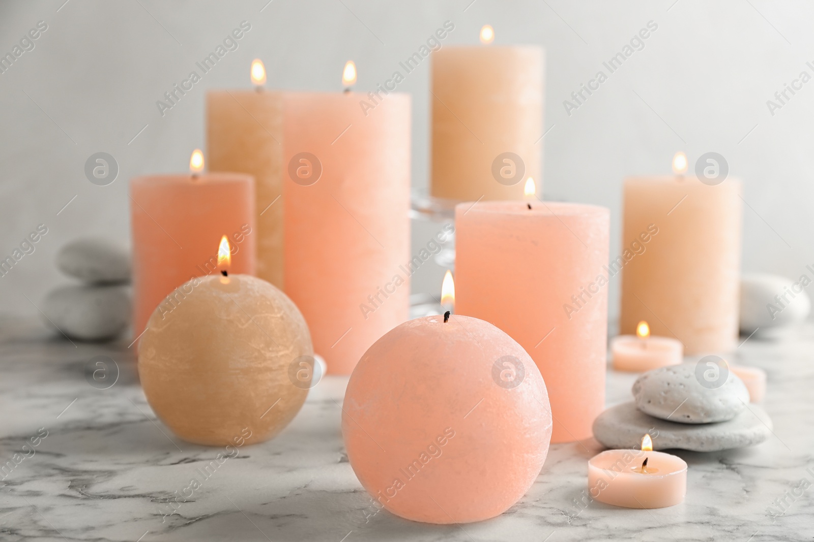 Photo of Composition of burning candles and spa stones on table. Space for text