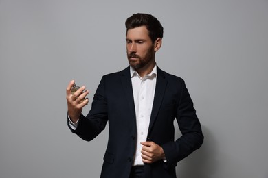 Handsome bearded man with bottle of perfume on light grey background