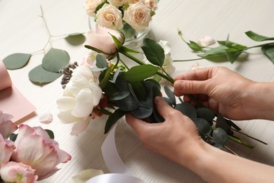 Photo of Florist creating beautiful bouquet at white table, closeup