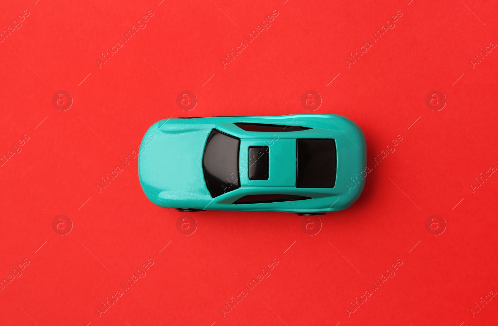 Photo of One light blue car on red background, top view