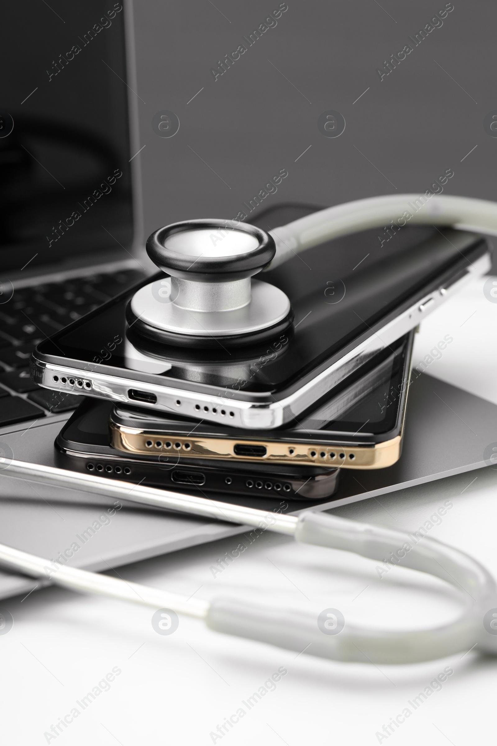 Photo of Stack of electronic devices and stethoscope on white table