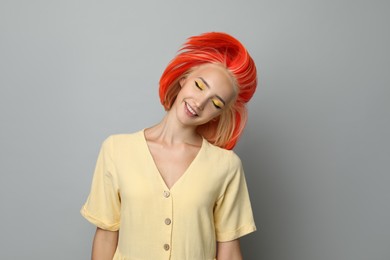 Photo of Beautiful young woman with bright dyed hair shaking head on light grey background