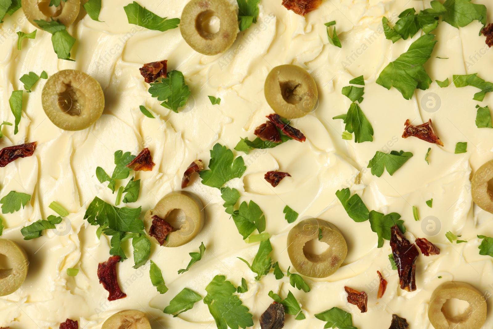 Photo of Fresh natural butter with cut olives, parsley and sun-dried tomatoes as background, top view