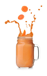 Image of Carrot slices falling into mason jar of fresh juice with splashes on white background