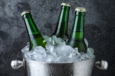 Metal bucket with beer and ice cubes on grey background, closeup